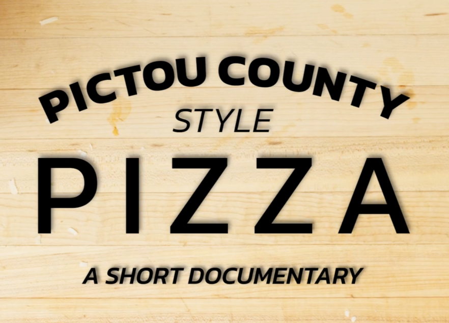 A cutting board with the text Pictou County Style Pizza A Short Documentary
